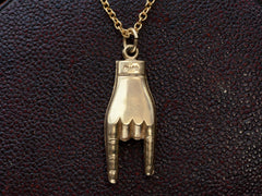 thumbnail of Backside of vintage gold hand pendant gesturing the sign of the horns, on dark textured background. A faint "14K" mark is visible.