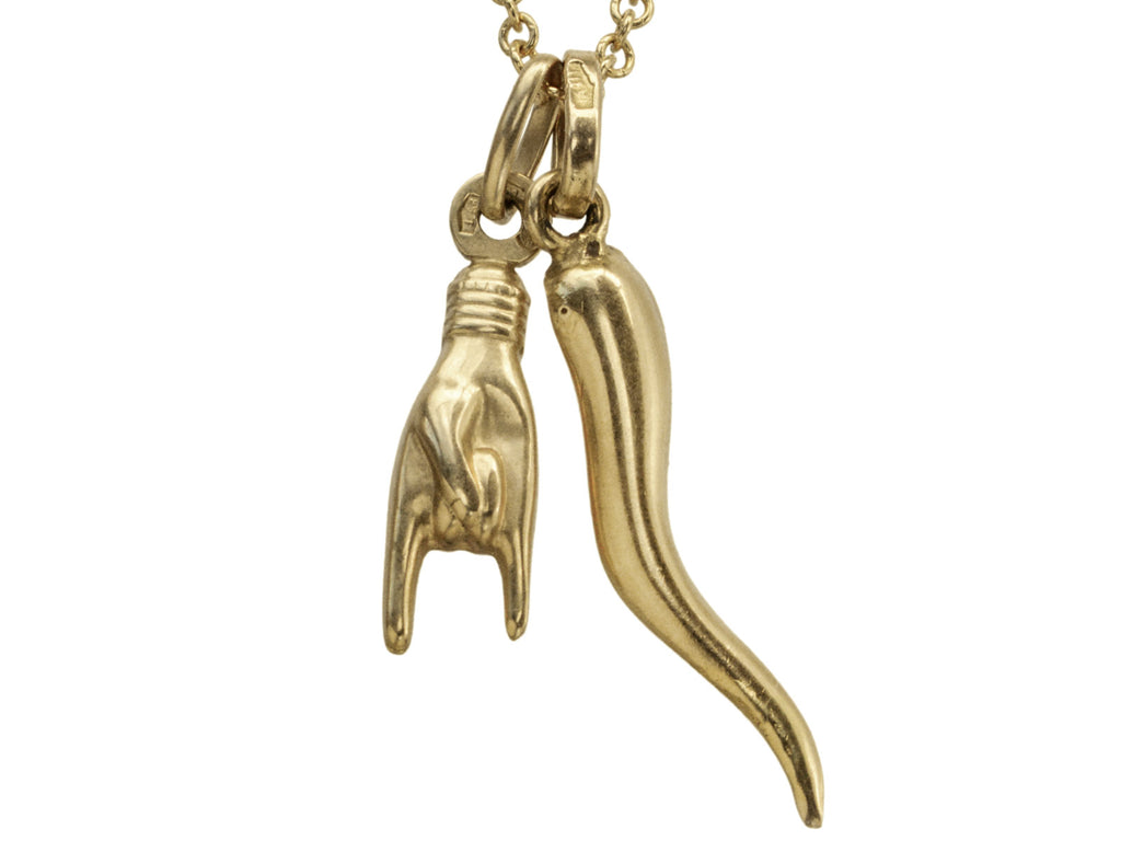 Detail of vintage 18K Italian charms, one of a hand gesturing the sign of the horns, the other of a cornicello horn, hanging together of cable chain. Shown on white background.