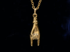 thumbnail of A c1980 yellow gold hand charm gesturing the sign of the horns, shown on black background.