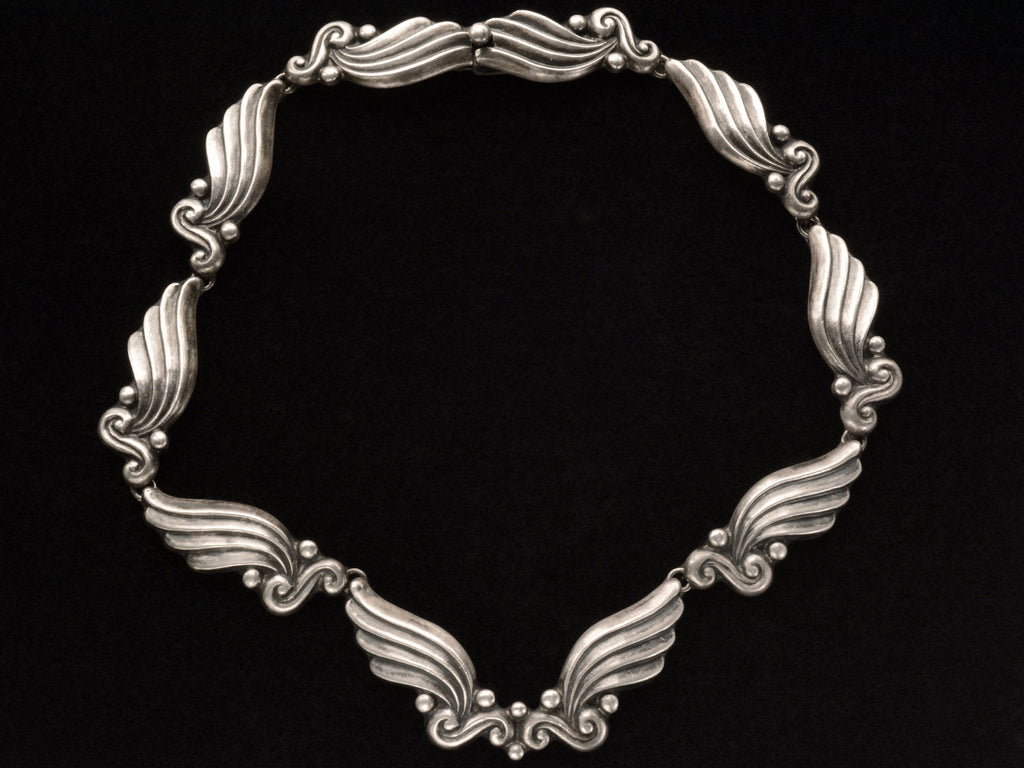 Silver vintage Margot de Taxco necklace with wing-like design on a black background