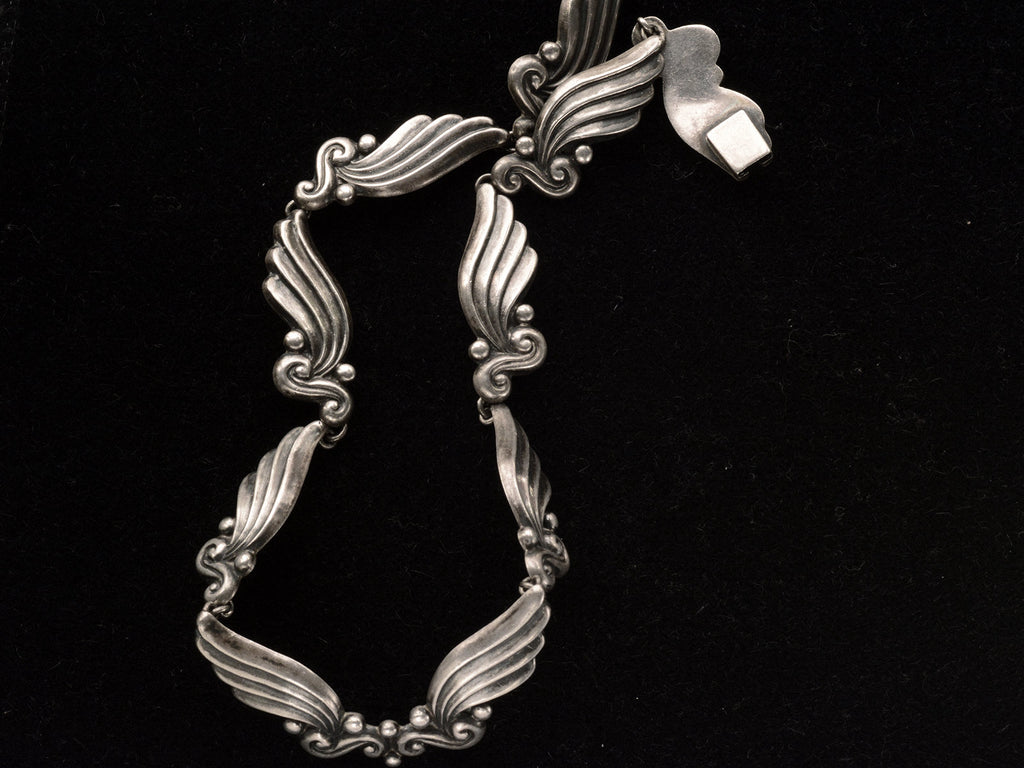 Detail of silver vintage Margot de Taxco necklace with wing-like design on a black background