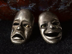 thumbnail of A pair of oxidized silver theatrical mask stud earrings depicting tragedy and comedy. On dark background.