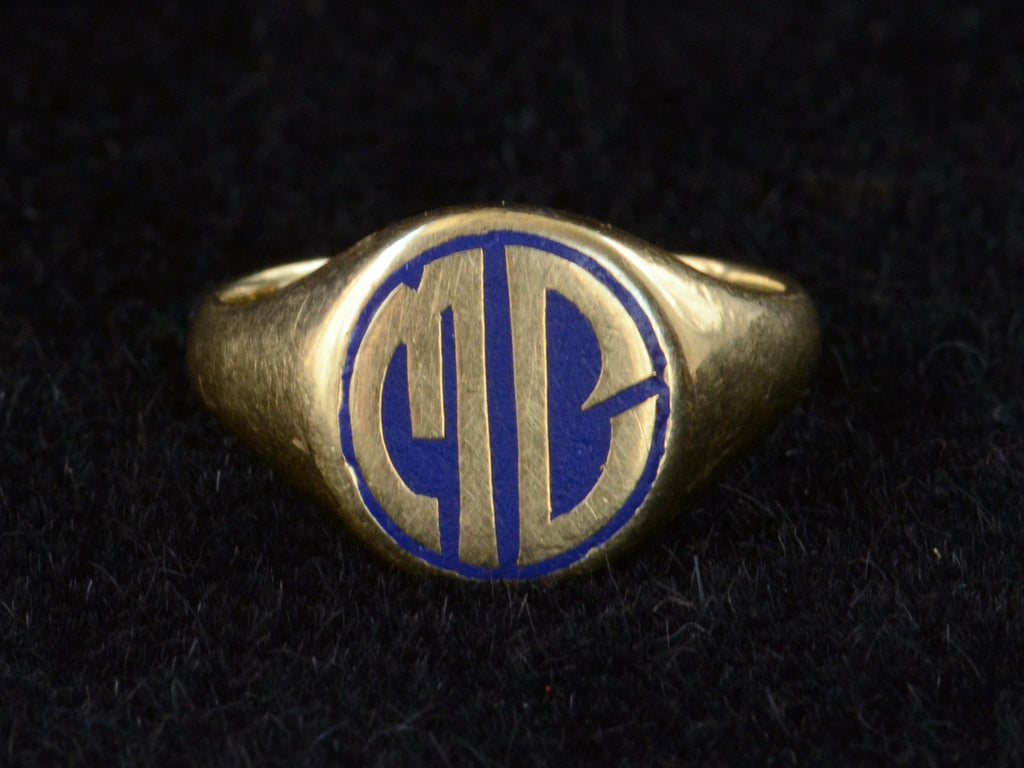 Face on view of c1920 Round Signet Ring in Yellow Gold with the initials MC in blue enamel, shown on black background