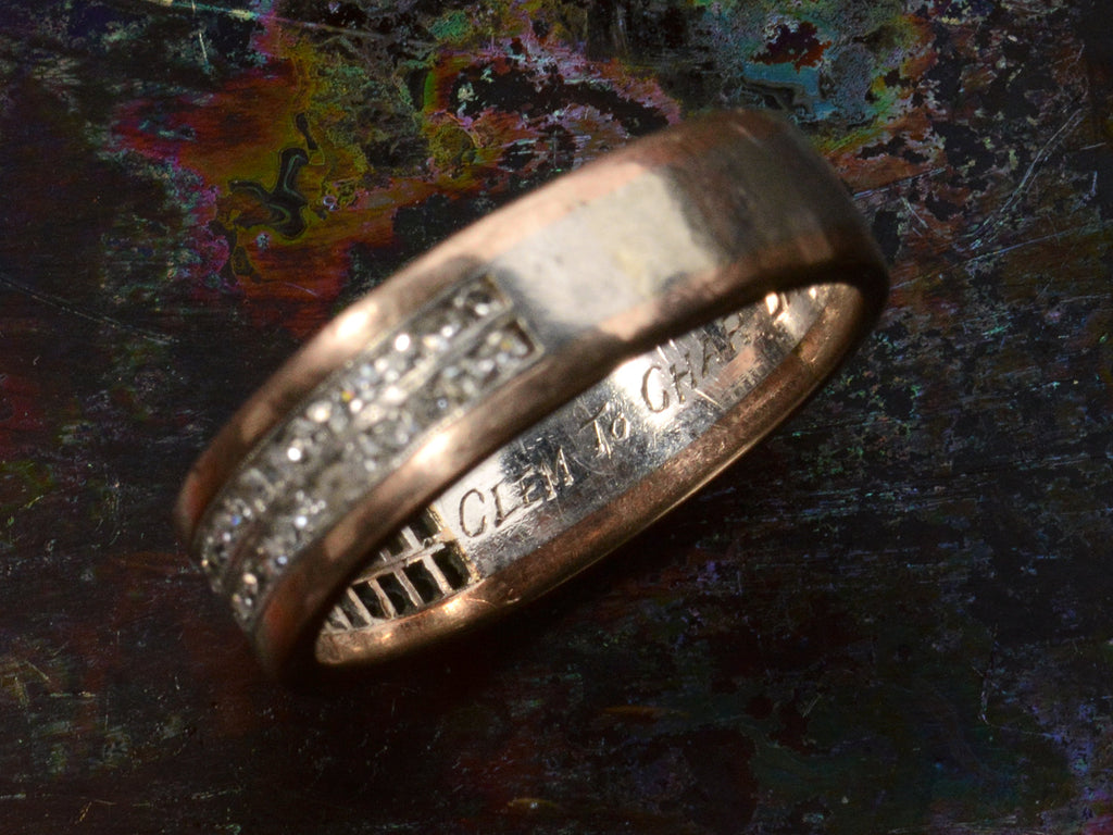 Detail view of inscription inside of vintage Men's Diamond Band in Platinum and Rose Gold (shown dark colorful background). The text "CLEM TO CHAR" is visible.