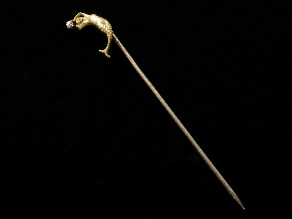 c1890 Yellow Gold Mermaid Stick Pin with a diamond, shown on black background.
