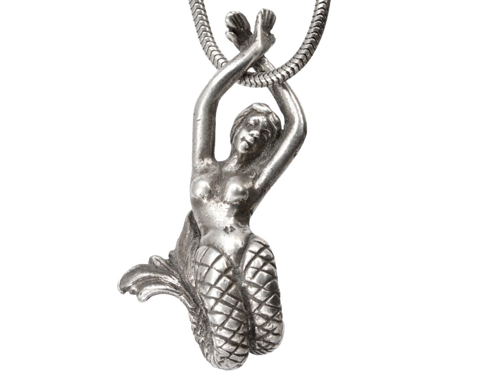 Detail of vintage silver mermaid pendant on snake chain, on white background.
