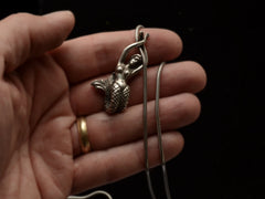 thumbnail of Detail of vintage silver mermaid pendant on snake chain, held in hand.