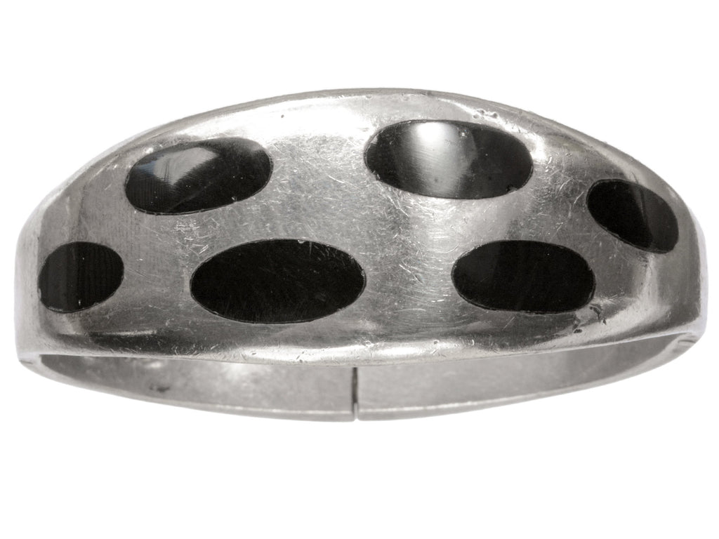 A vintage silver bracelet with inset oval black onyx polka-dots, shown on white background.
