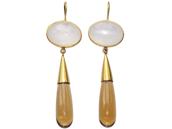 Pair of 18K yellow gold earrings with oval moonstone tops and amber-colored quartz teardrop pendants, shown on white background.
