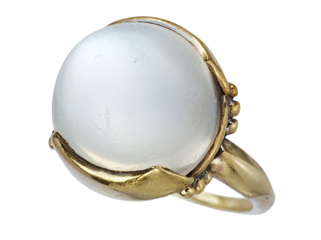 Right angled view of vintage gold ring with silvery blue moonstone orb, shown on white background.