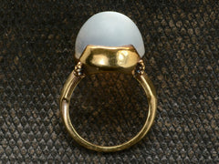 thumbnail of Side profile view of vintage gold ring with silvery blue moonstone orb, shown on dark textured background.