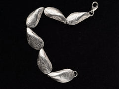 thumbnail of Silver bracelet with mussel shell links, on black background.