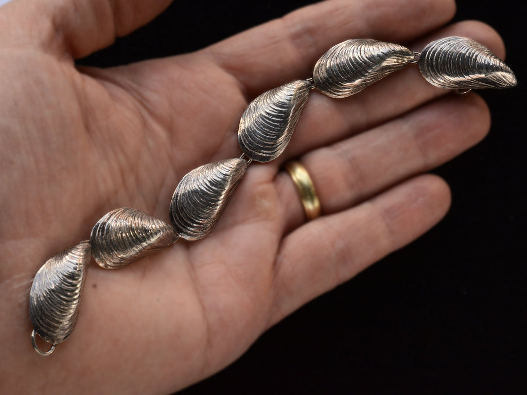 Silver bracelet with mussel shell links, on hand.