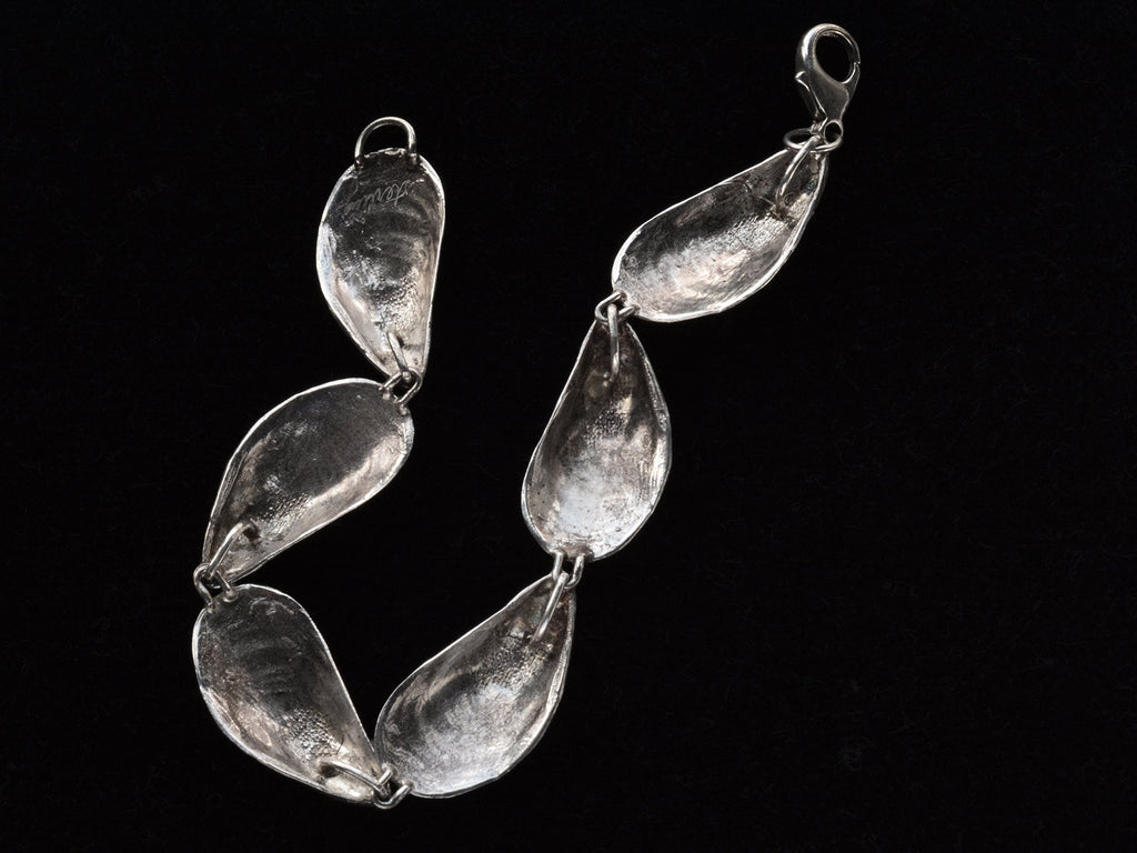 Reverse side of bracelet with mussel shell links, on black background. Inscribed "Sterling"