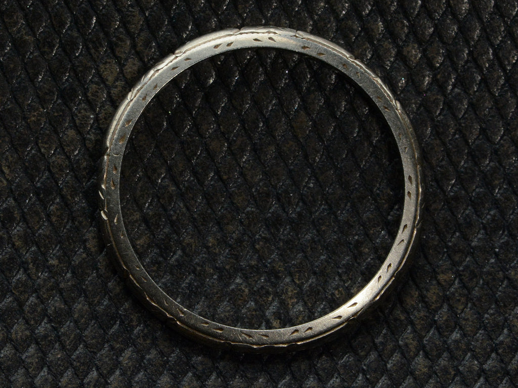 Side profile of c1930 Patterned Narrow 18K White Gold Wedding Band, on dark textured background.