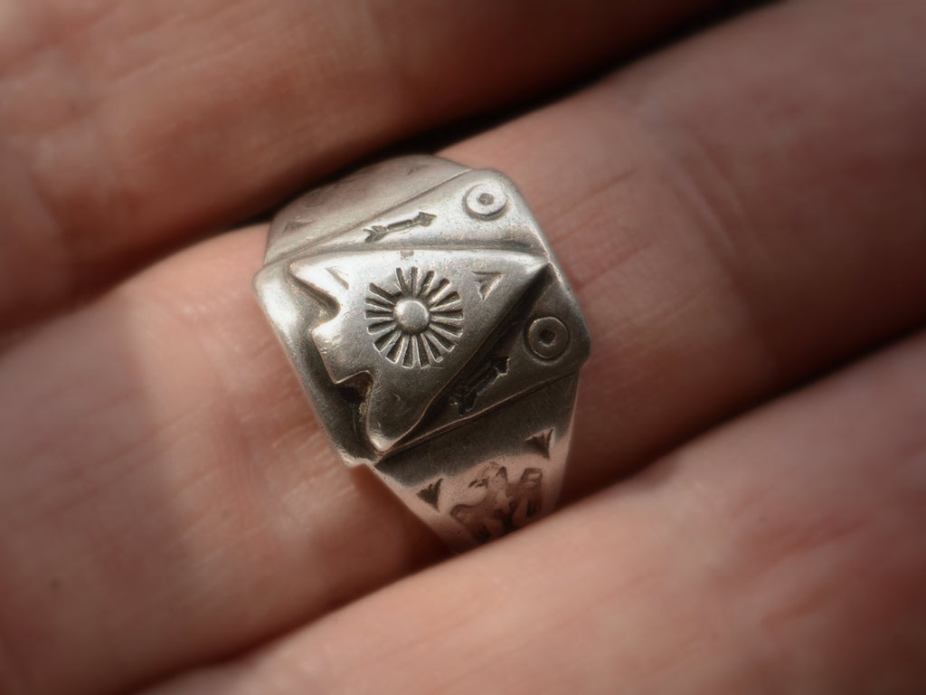 Front view of c1930 Navajo silver signet ring with an arrowhead design and eagles stamped on the shoulders, shown on finger