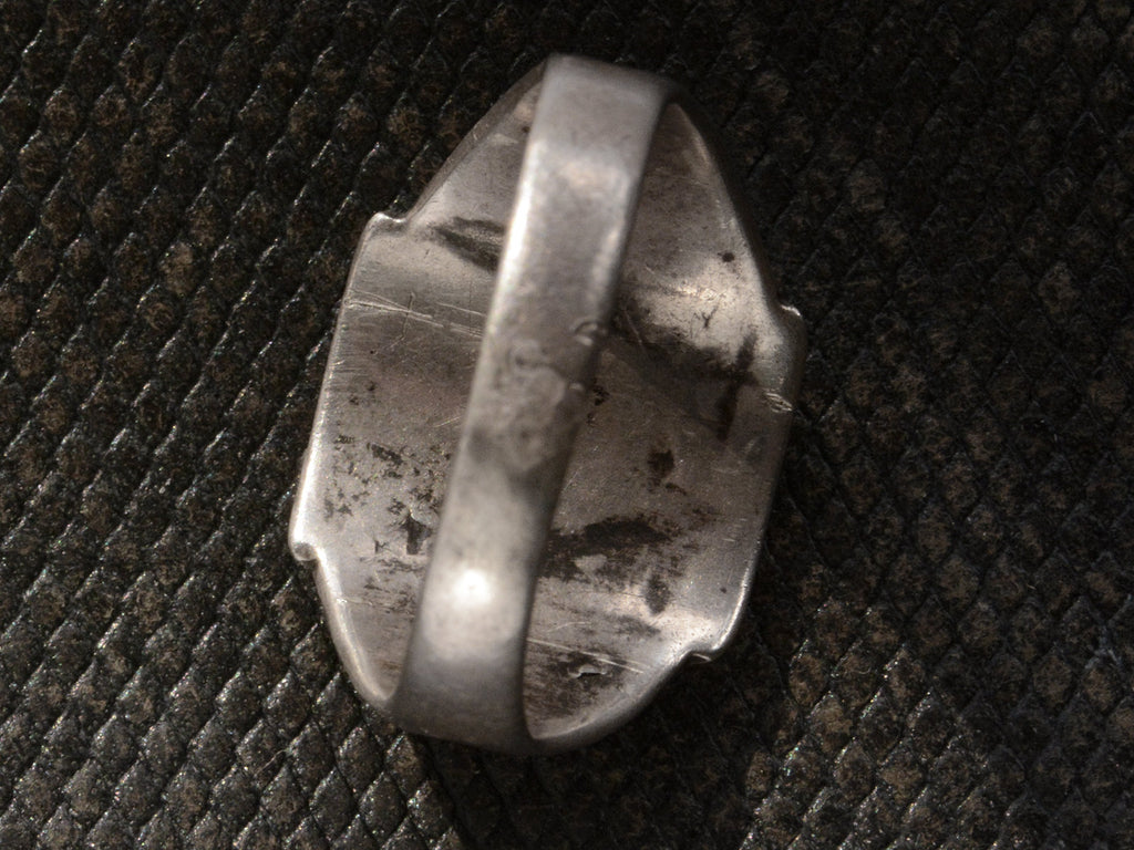 Underside view of c1930 Navajo silver signet ring, shown on dark textured background.