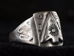 thumbnail of Side view of c1930 Navajo silver signet ring with an arrowhead design and eagles stamped on the shoulders, shown on dark background.