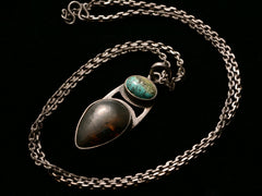 thumbnail of Angled view of silver pendant with oval turquoise and pear shaped tortoiseshell, on long chain, on black background.