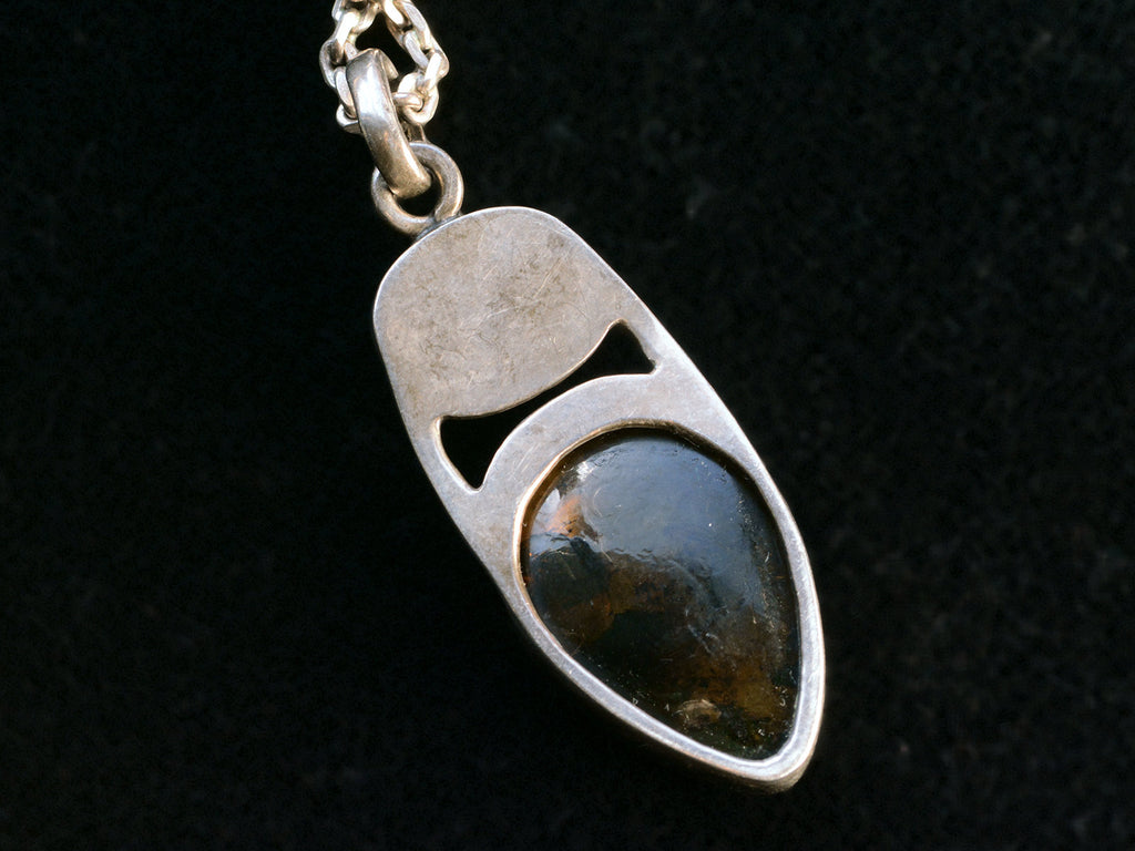 Reverse side of silver pendant on black background.
