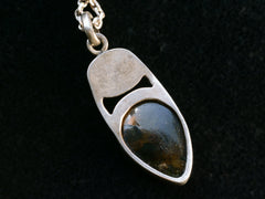 thumbnail of Reverse side of silver pendant on black background.