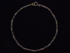 thumbnail of An antique chain of alternating silver and black striped links and gold filled links. Shown laid out on black background.