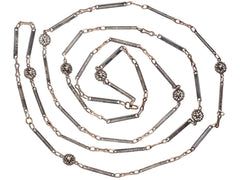 thumbnail of A 19th century long chain with alternating niello striped bar links, gold filled links, and silver rosettes, shown spiraled on white background.