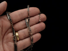 thumbnail of A 19th century long chain with alternating niello striped bar links, gold filled links, and silver rosettes, shown held in hand.