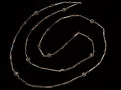 thumbnail of A 19th century long chain with alternating niello striped bar links, gold filled links, and silver rosettes, shown spiraled on black background.