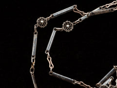 thumbnail of Detail of a 19th century long chain with alternating niello striped bar links, gold filled links, and silver rosettes, shown on black background.