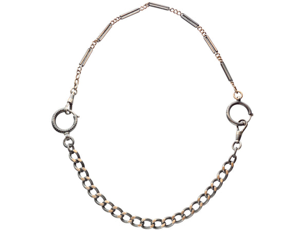 A necklace composed of a pair of gold filled and niello silver watch chains, on white background. 