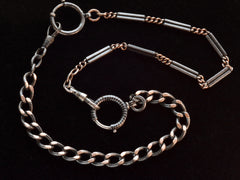 thumbnail of Close up of a necklace composed of a pair of gold filled and niello silver watch chains, on black background. 