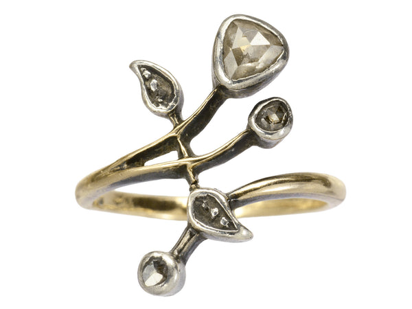 An antique Art Nouveau gold and silver ring with rose cut diamonds in a floral design. Shown on white background.