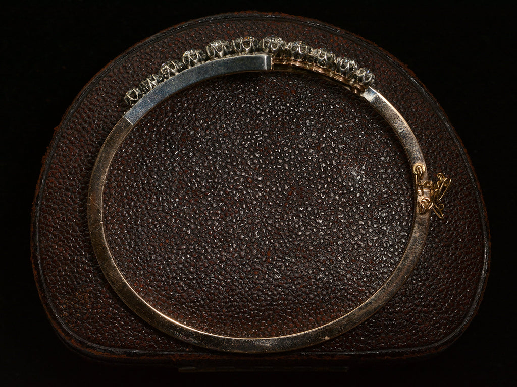 Side profile of a platinum topped yellow gold Art Nouveau bracelet with rows of old European cut and rose cut diamonds, shown on dark textured background.