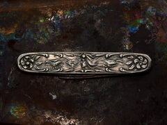 thumbnail of Art Nouveau silver pocket knife with imagery of a woman and flowers, shown on dark iridescent background.