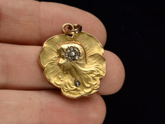 thumbnail of c1910 Art Nouveau yellow gold pansy shaped pendant with the profile of a woman (shown hand for scale)