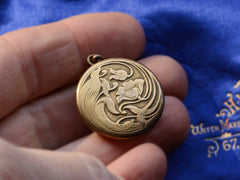 thumbnail of c1920 Gilt Art Nouveau Locket with Flower Motif held in hand.