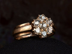 thumbnail of Left angled view of antique rosy-yellow gold ring with cluster of old mine cut diamonds, on black background.