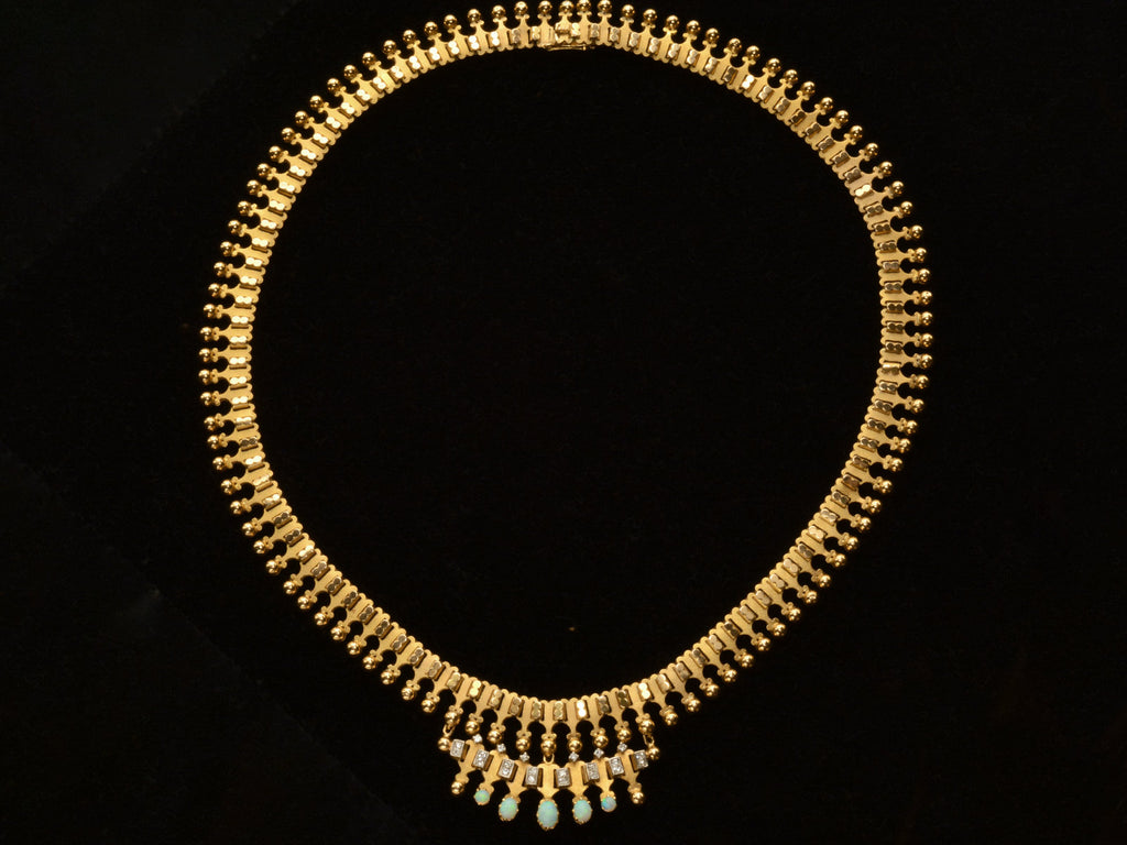 A c1930 Victorian-style 18K rosy-yellow gold collar with a small front bib of opals and diamonds, shown on black background.