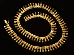 thumbnail of A c1930 Victorian-style 18K rosy-yellow gold collar shown spiraled on black background.