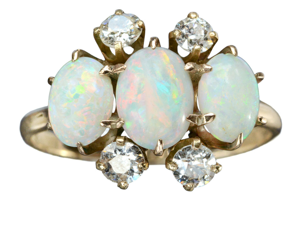 A vintage gold ring featuring three oval white opal stones and four round diamonds, set in gold against a plain white background.
