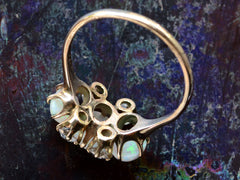 thumbnail of Inside view of a vintage gold ring featuring three oval white opal stones and four round diamonds, set in gold against a dark iridescent background.
