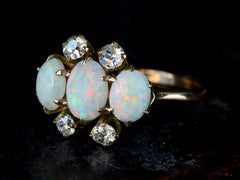 thumbnail of A vintage gold ring featuring three oval white opal stones and four round clear diamonds, set against a dark background.