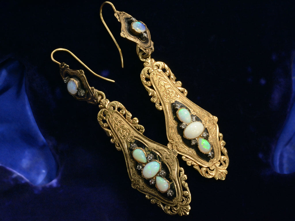 Angled view of c1860 Opal & Black Enamel Earrings (shown on dark blue background)