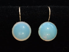 thumbnail of A vintage pair of round opaline glass earrings with blackened silver settings and 14K yellow gold ear wires. Shown on black background.