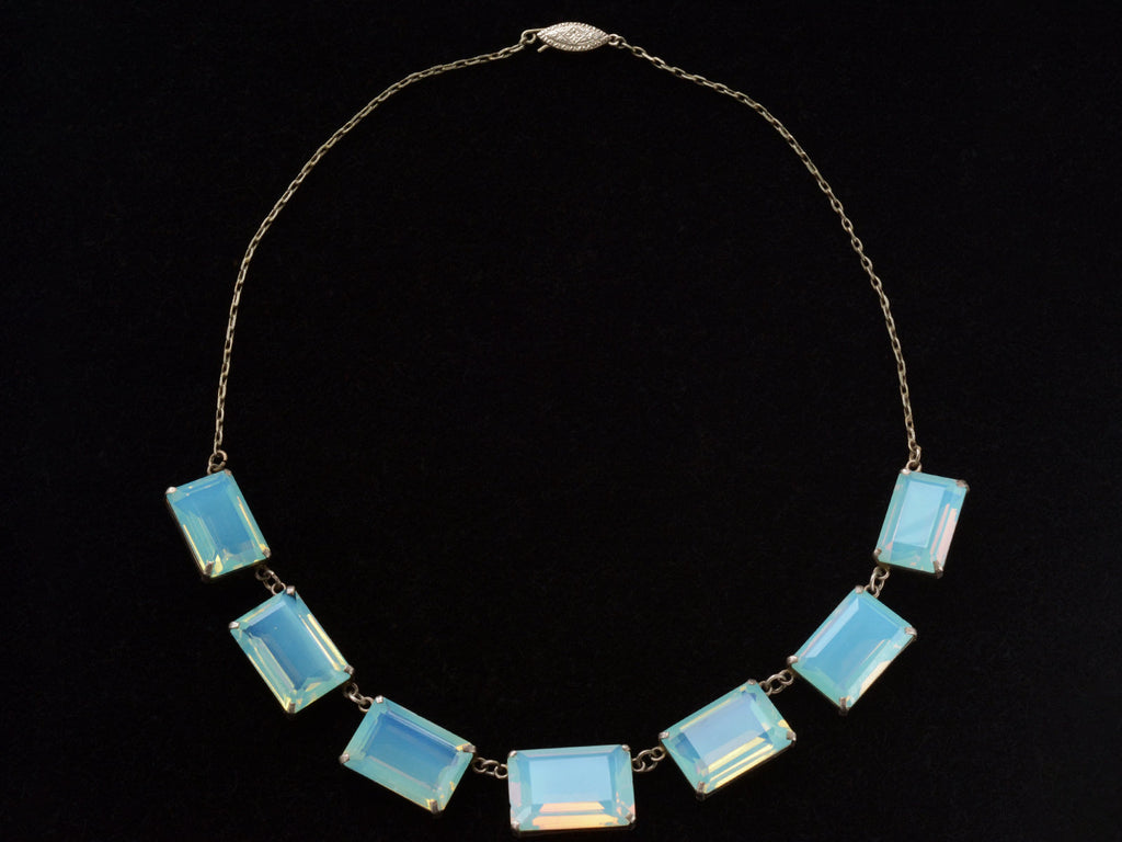 Full view of vintage c1950 silver necklace with a bib of rectangular opalescent glass stones, shown on black background.
