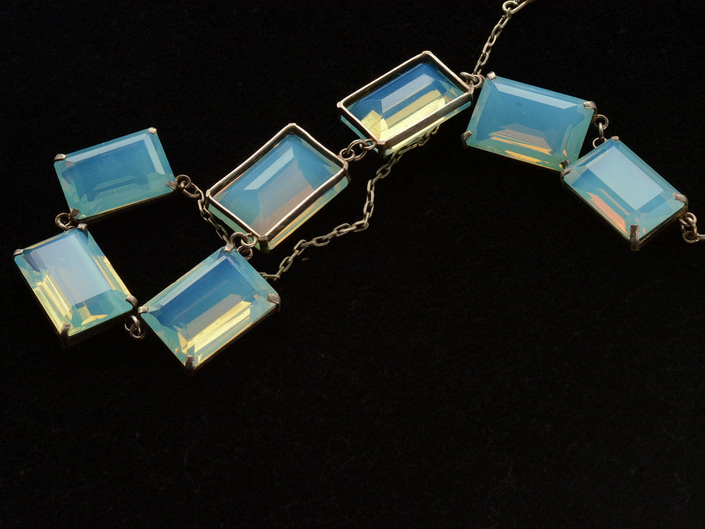 Detail view of reverse side of vintage c1950 silver necklace with a bib of rectangular opalescent glass stones, shown on black background.
