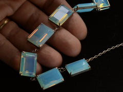 thumbnail of Detail view of vintage c1950 silver necklace with a bib of rectangular opalescent glass stones, shown in hand.