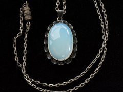 thumbnail of Detail of a vintage oxidized silver necklace with an oval opaline glass pendant, shown with chain clasp, on black background.