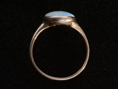 thumbnail of Side profile view of c1920 oval opal ring in rosy 10K gold, shown on black background.